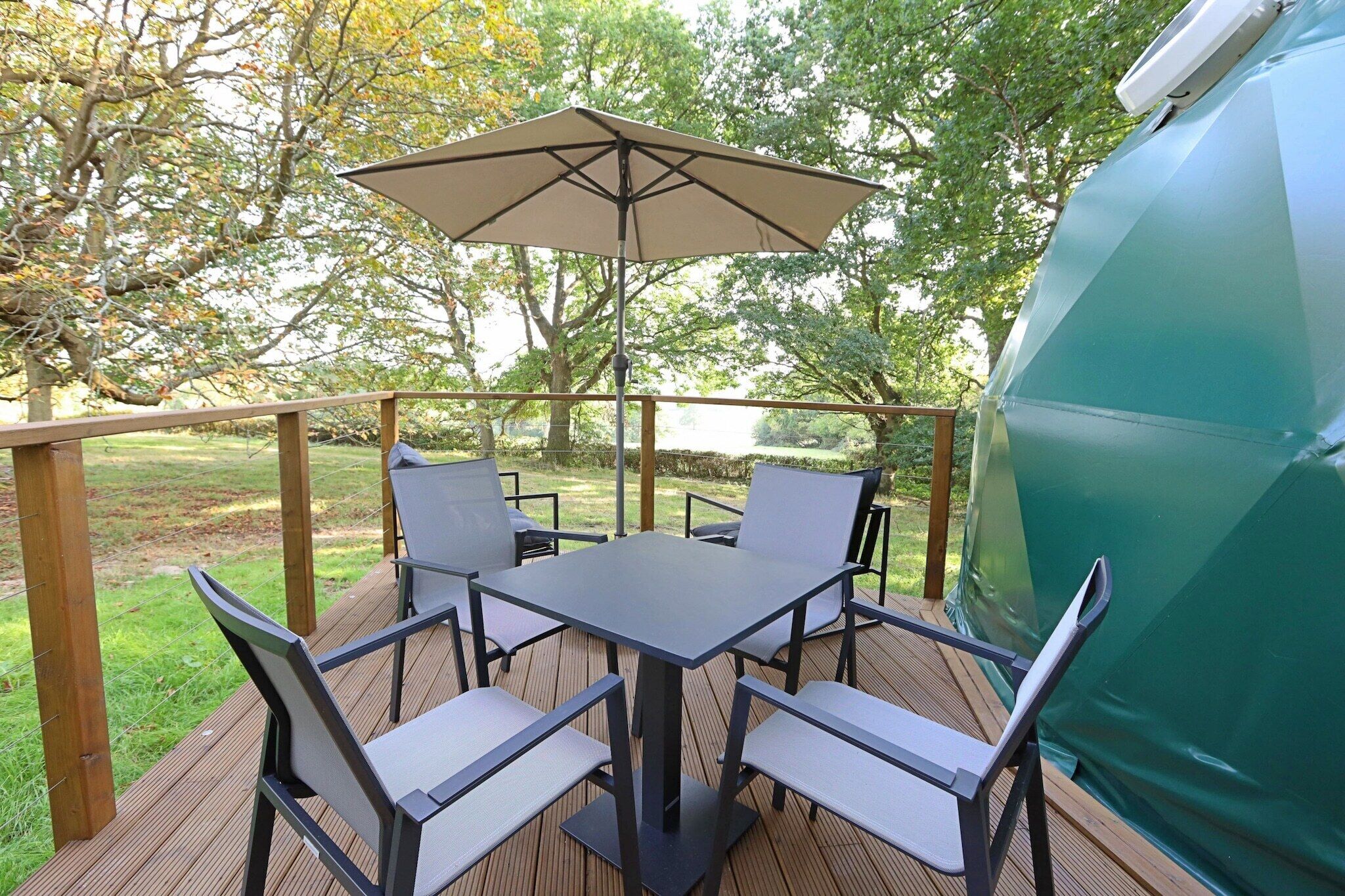 Une terrasse avec une table et des chaises, un parasol et un barbecue.