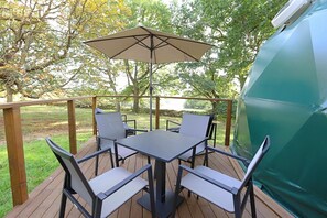 A deck with a table and chairs, an umbrella, and a grill.
