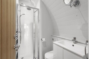 A modern bathroom with a glass-enclosed shower, a white sink, and a toilet.