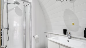 Un bagno moderno con box doccia in vetro, un lavabo bianco e uno specchio sopra il lavabo.