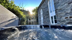 A stone building with a hot tub in front, surrounded by greenery. - Chapel in Snowdonia with Hot Tub & Games Room (Dinas Mawddwy)