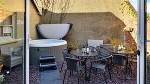 Terrassa exterior amb un bany d'hidromassatge, cadires de vimetla i taula preparada per dinar.