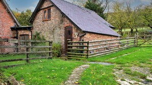 Un bâtiment rustique en pierre, doté d’un toit en pente, d’une porte en bois et d’un chemin de terre qui y mène.