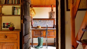 Un intérieur rustique en bois, avec une bibliothèque, un chapeau, une canne à pêche et des bottes en caoutchouc vertes.