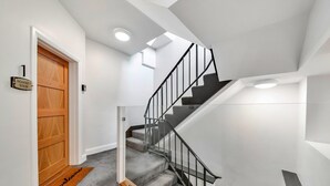 A modern staircase with a wooden door and a welcome mat.