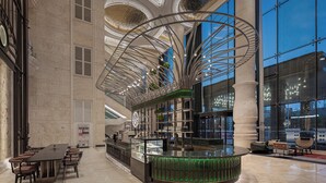 Un hall d’entrée spacieux avec un bar central, un coin salon doté d’une longue table et un lustre moderne.