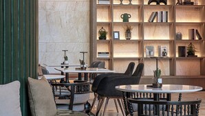 Une bibliothèque moderne avec des étagères, une table ronde et un canapé vert.