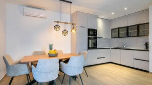 Una cocina moderna con armarios blancos, una mesa de comedor de madera y sillas azul claro.
