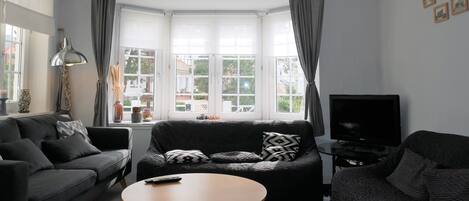 A modern living room with a sofa, a round coffee table, and a television.