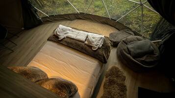 Une tente confortable avec un lit, des oreillers et une couverture.