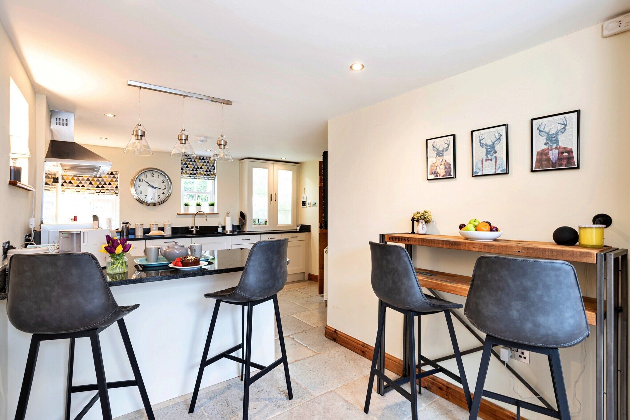A modern kitchen with a central island, bar stools, and a clock on the wall.