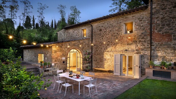 Un bâtiment en pierre doté d’un patio, d’un espace extérieur aménagé avec des sièges et de guirlandes lumineuses.