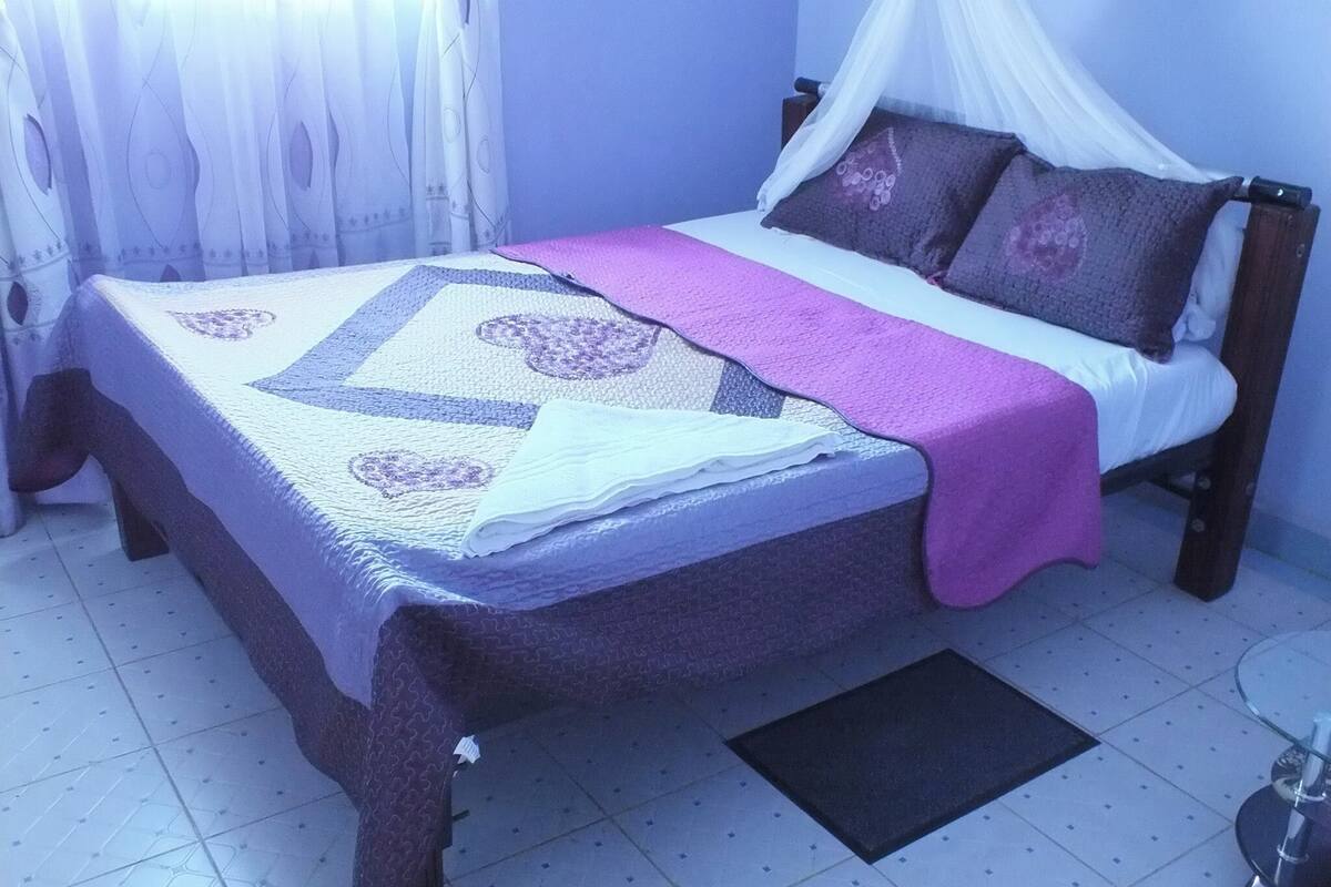 Un lit à baldaquin, une couvre-lit à motifs et des oreillers.