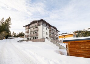 A multi-story building with balconies, a ski slope in the foreground, and a mountainous backdrop. - Penthouse in Katschberghohe With Balcony (Rennweg am Katschberg)