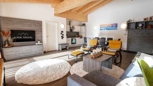 A modern living room with a TV, sofa, chairs, and a dining area.