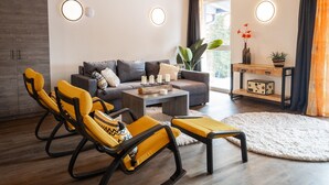 A modern living room with a grey sofa, yellow chairs, a coffee table, and a wooden ceiling.