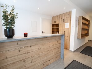 A reception desk with a wooden panel design, a potted plant, and a red candle. - Penthouse in Katschberghohe With Balcony (Rennweg am Katschberg)