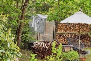 A rustic outdoor setting with a wooden chair, a pile of logs, and a clothesline.