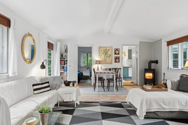 A cozy room with a sofa, a dining table, a fireplace, and a bookshelf.