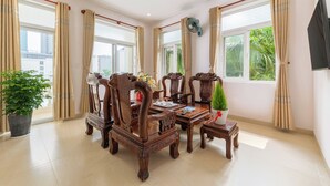 A spacious room with a large dining table, elegant wooden chairs, and a potted plant. - Villas De Mykhe (Da Nang)