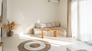 Ein modernes Wohnzimmer mit einer Couch, einem Couchtisch und einem großen Fenster mit durchsichtigen Vorhängen.