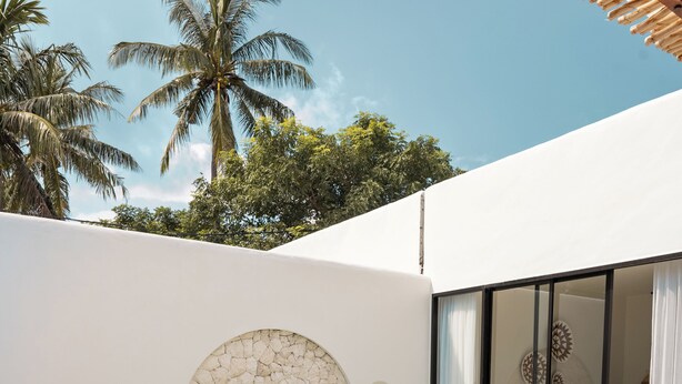 Ein moderner Poolbereich mit Liegestühlen, einer Steinwand und einem gläsernen Raum.