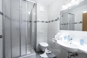 Ein modernes Badezimmer mit Duschkabine aus Glas, einer weißen Toilette und einem Waschbecken mit Spiegel.