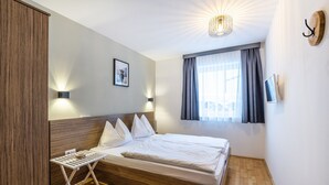 Ένα στρωμένο κρεβάτι με μαξιλάρια, ένα μικρό τραπεζάκι με ένα δίσκο και μια τηλεόραση τοποθετημένη στον τοίχο.
