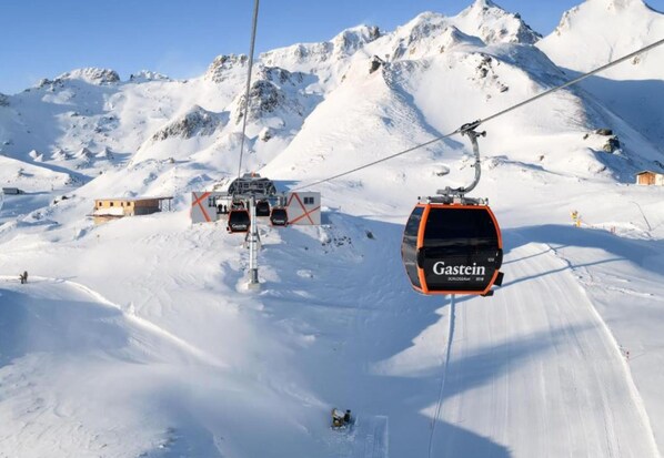 Lumisen vuoristoalueen hiihtohissi, jonka istuimessa on kyltti, jossa lukee ”Gastein”.