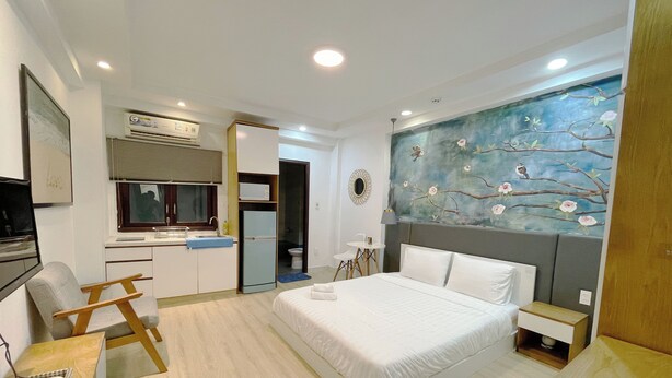Une chambre d’hôtel moderne, équipée d’un lit, d’un bureau, d’une chaise, d’une petite table et d’un tableau au mur.