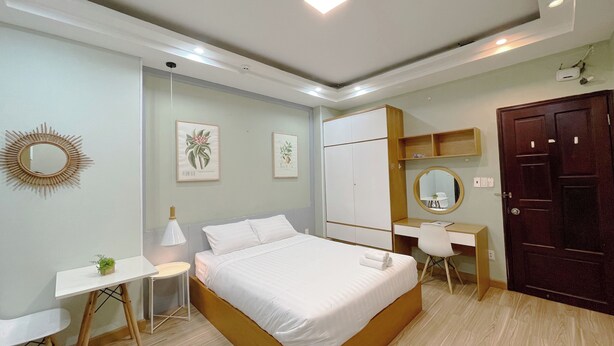Quarto moderno com cama, mesa de cabeceira, escrivaninha, guarda-roupa e espelho.