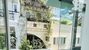 Un balcon doté d’une rambarde en treillis blanc, d’un mur en pierre et offrant une vue sur les bâtiments voisins.