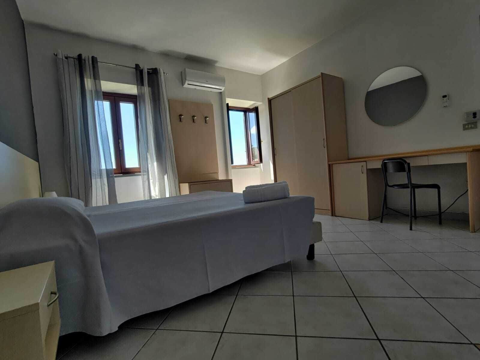 Una moderna camera d'albergo con un letto, una scrivania, una sedia e un armadio.
