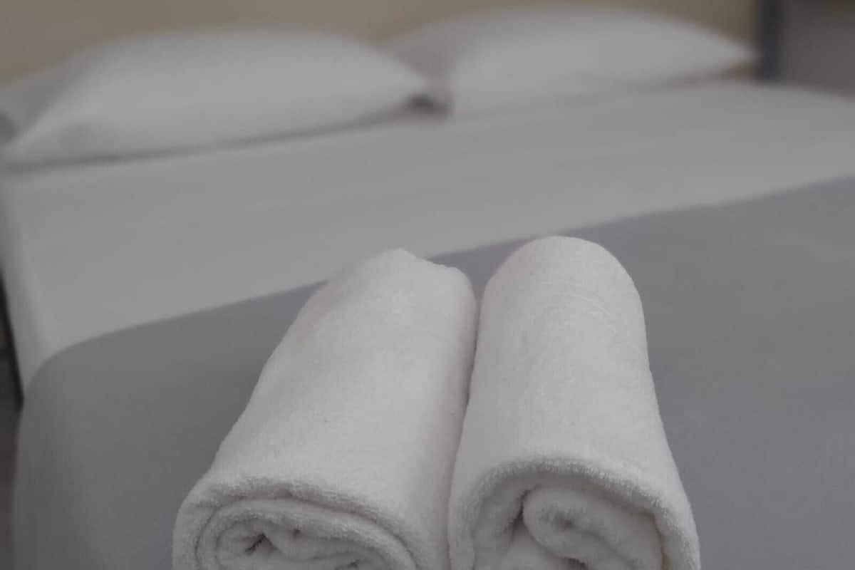 A neatly made bed with white linens and pillows.