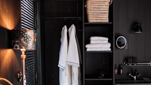 Une chambre à coucher moderne avec une armoire en bois foncé, une table de chevet avec une lampe et des serviettes soigneusement pliées.
