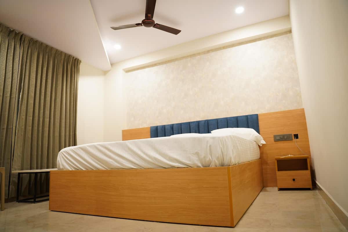 A bedroom with a wooden bed, a nightstand, a ceiling fan, and a window with curtains.