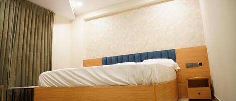 A bedroom with a wooden bed, a nightstand, a ceiling fan, and a window with curtains.