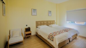 A bedroom with a bed, a chair, a nightstand, and two wall-mounted pictures. - Moon in 9 haus Cafe & Villas (Rayong)