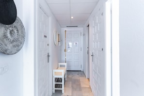 Un couloir avec des portes blanches, un banc et un miroir fixé au mur.