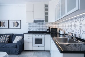 Una cocina moderna con armarios blancos, encimera negra y un respuesto con diseño.