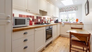 A kitchen with white cabinets, a microwave, a stove, and a wooden table.