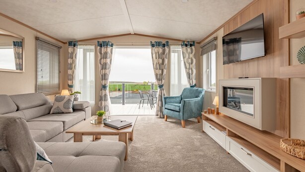 Ein modernes Wohnzimmer mit Sofa, Sessel, Couchtisch und Fernseher.