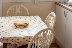 Une table à manger recouverte d’une nappe à pois et sur laquelle est posée une pile de sets de table en fibres tressées.