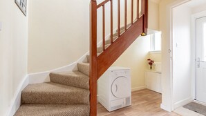 Una escalera con barandas de madera, escalones alfombrados y una pared blanca.