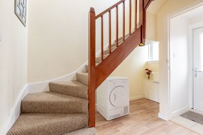 Eine Treppe mit Holzwangen, Teppichstufen und einer weißen Wand.