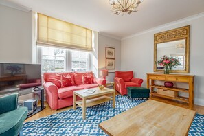 Una sala de estar con televisor, dos sofás, una mesa de centro y un espejo grande.