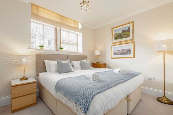 A neatly arranged bedroom with a bed, bedside tables, a window with blinds, and wall-mounted pictures. - Southgait Hall (No 4) | St Andrews (St Andrews)