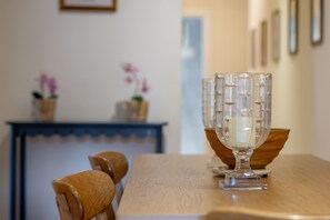 A dining table with a clear glass centerpiece, wooden chairs, and a blue table runner. - Southgait Hall (No 4) | St Andrews (St Andrews)