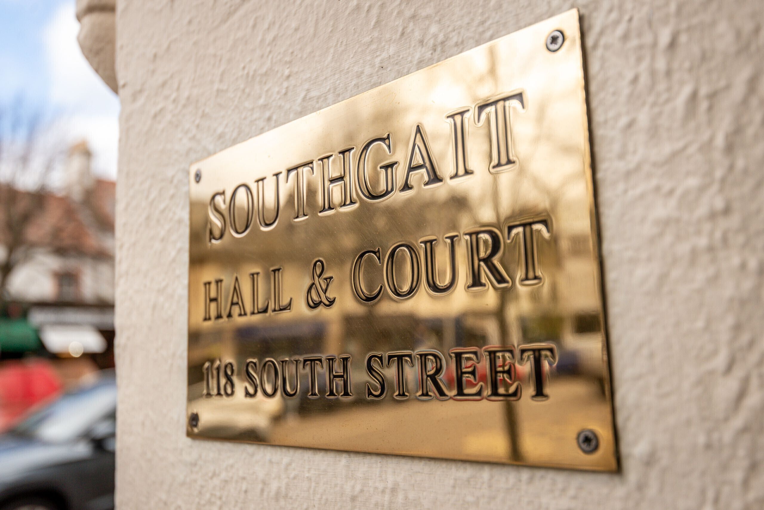 A brass plaque on a wall with the text "Southgate Hall & Court 118 South Street".