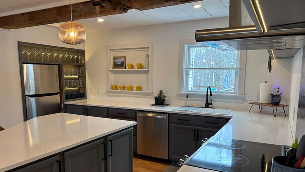 A modern kitchen with a large island, built-in appliances, and a window providing natural light. - Timber Tide Retreat Just 15 Minutes to Belfast (Swanville)